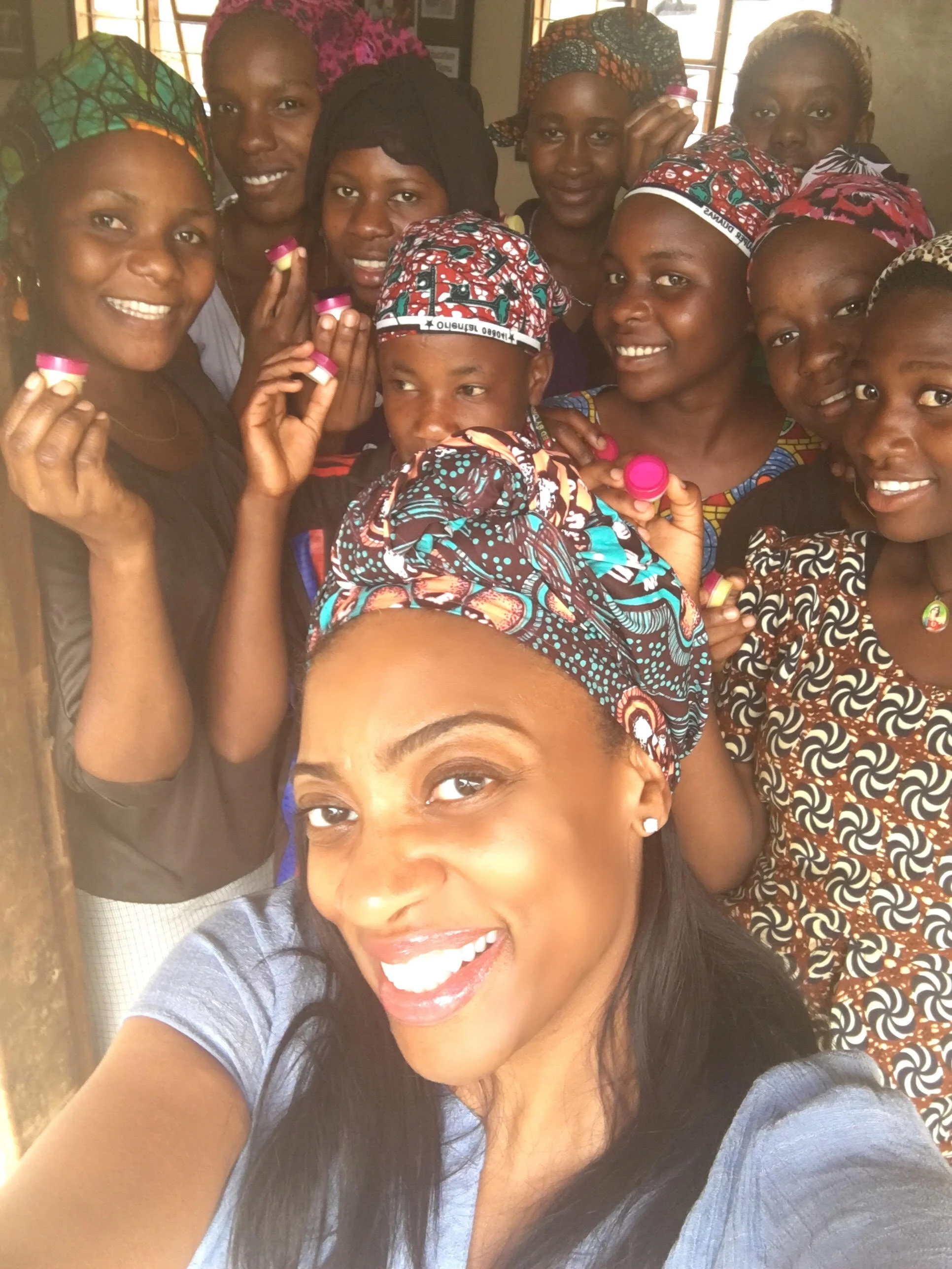Deida Massey with women and girls at Uzima Center holding Bixa Beauty products